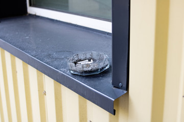 Glass ashtray on the windowsill outside closeup