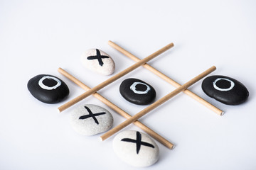 tic tac toe game with grid made of paper tubes, and pebbles marked with naughts and crosses on...