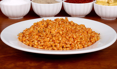 Cooked bulgur with delicious tomato sauce ready to serve on a white plate