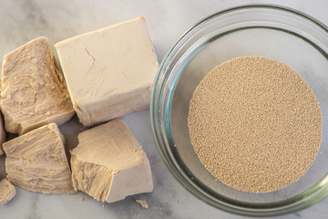 dried and fresh yeast on a white kitchen bacground with wooden rolling pin