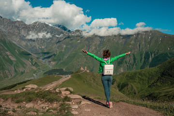 Curly young woman enjoying the view in the top of mountain on a hot summer day. Lifestyle concept. Back view. mountain landscape. Freedom concept.