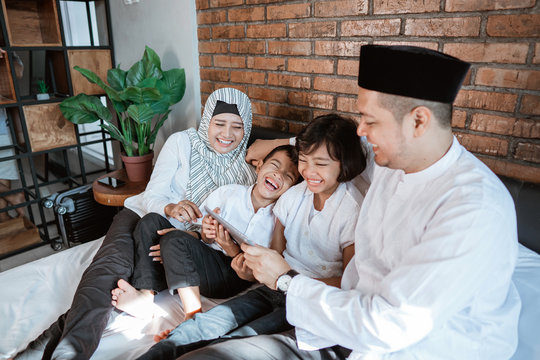 happy asian family on ramadan kareem using tablet pc for social interaction with friend - Powered by Adobe
