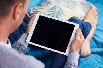 man using a tablet lying on a couch