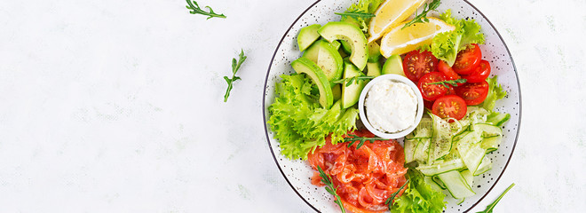 Salad of salted fish salmon, avocado, cherry tomatoes, cucumber, lettuce and cream cheese. Fish menu. Dietary menu. Seafood - salmon. Top view, overhead, banner