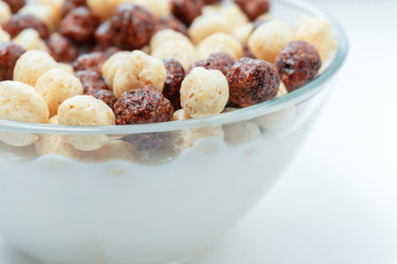 Breakfast cereal white chocolate balls close-up selective focus in milk background.