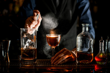 bartender holds glass of drink with his hand and sprinkles on it