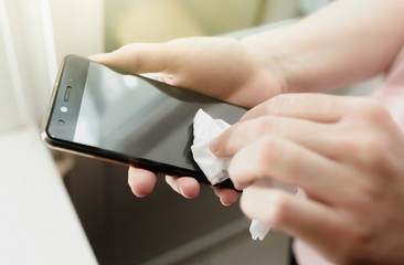 close-up female hands wipe smartphone with wet wipe from viruses