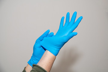 A woman puts on a blue medical glove. Coronavirus outbreak concept