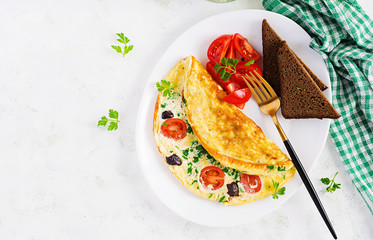 Breakfast. Omelette with tomatoes, black olives, cottage cheese and green herbs on white plate.  Frittata - italian omelet. Top view