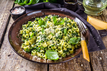 Ditaloni rigati spring recipe, Green ditalini pasta with spinach, green pesto sauce and cheese, rustic wooden background