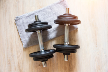 Two dumbbells lie on the floor with a towel, home workout.