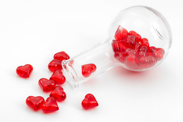 The chemicals of love and of the science of attraction concept with chemistry flask with glossy red heart falling out of it isolated on white background