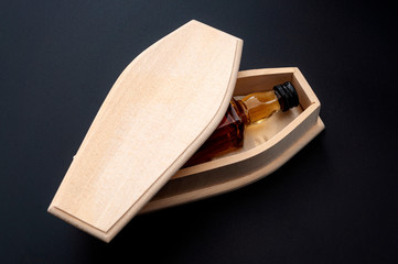 Alcohol abuse kills, despair deaths and drinking problem concept with liquor bottle in wood coffin...