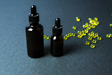 Moisturizing and healing skin serum with vitamin C on a black background. Vitamin capsules as a...