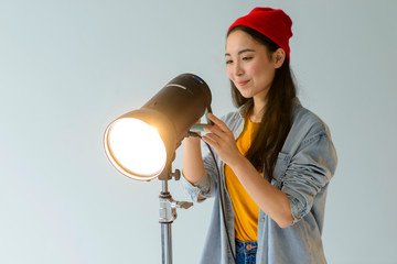Woman adjusting light. Asian girl in photography studio.