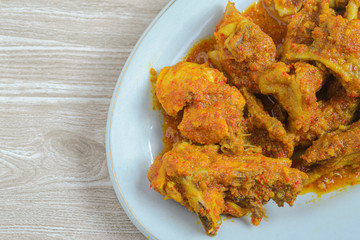 Ayam rica-rica in white plate. Indonesian food made from chicken and various seasonings. has a spicy taste. wooden background