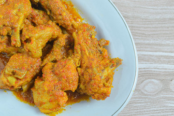 Ayam rica-rica in white plate. Indonesian food made from chicken and various seasonings. has a spicy taste. wooden background