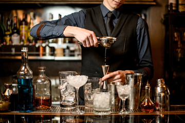 Fototapeta na wymiar male bartender squeezes juice into a steel jigger.