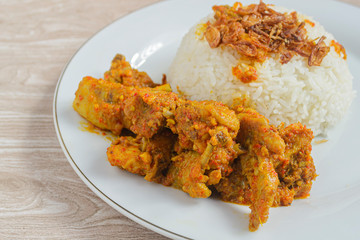 Nasi ayam rica-rica in white plate. Indonesian food made from chicken and various seasonings. has a spicy taste. wooden background
