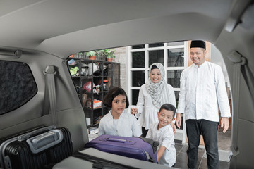 muslim family load their suitcase in to car trunk. preparing for eid mubarak holiday