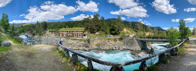 Fototapeta na wymiar Panorama eines reißenden Flusses in Norwegen, der an einem Haus vorbeiführt.