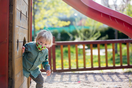 Blonde Little Toddler Child Inwearing Protective Mask, Playing On The Playground