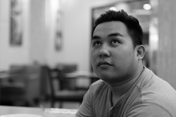 Obraz premium Face of young overweight Asian man thinking at the coffee shop
