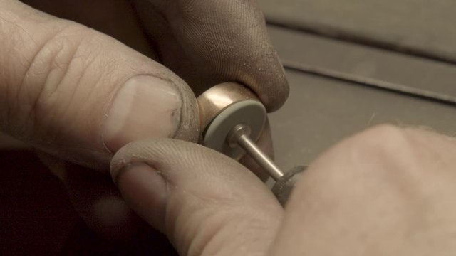 Jeweler polishes ring with a polishing wheel brush