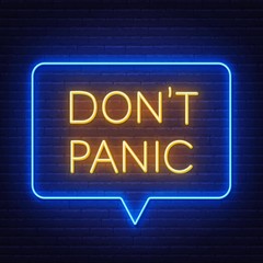 Don't panic neon lettering on brick wall background .