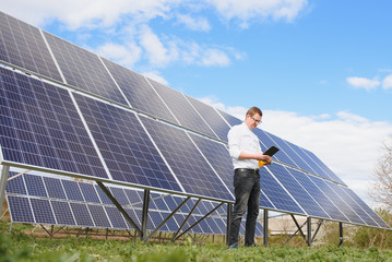 solar panels and blue sky.Man standing near solar panels. Solar panel produces green, environmentally friendly energy from the sun.