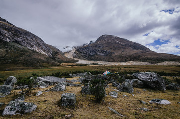 Taullipampa camp with tents and the remains of an avalanche in the background on the trekking of the quebrada santa cruz de peru