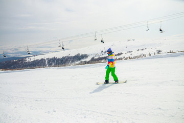 Fototapeta na wymiar Girl snowboarding on the ski slope in Tsakhkadzor (Tsaghkadzor), Kotayk Province, Armenia