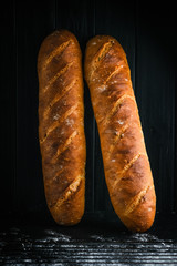 Traditional french baguettes on a dark background top view copy space.