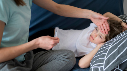 Mother checking his son for fever