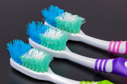 Old unusable worn-out toothbrushes on black background