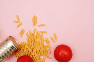a can of stew, spilled macaroni, and two red tomatoes on a pink background