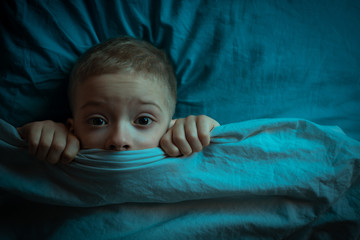 boy in bed with his eyes open. the child is afraid of the dark. tormented by nightmares and...