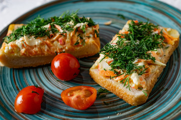 A couple of vegetable sandwiches on fresh white bread with cheese, carrots and crab meat, decorated with dill greens, next to cherry tomatoes and a fragrant garlic smell of snacks