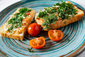 A couple of vegetable sandwiches on fresh white bread with cheese, carrots and crab meat, decorated with dill greens, next to cherry tomatoes and a fragrant garlic smell of snacks