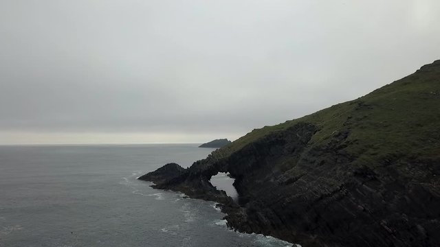 Flyover Irish misty coast with natural archway