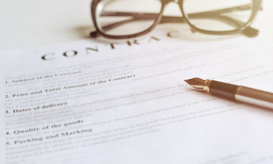 White table with paper contract detail and empty space to sign authorized signature, props with glasses and ink pen, copy space on the left