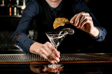 bartender holds martini glass and decorate it
