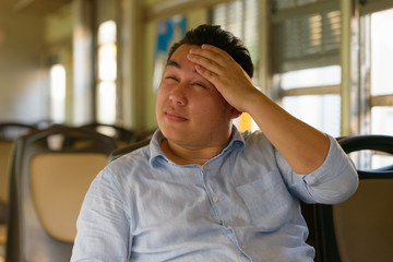 Obraz premium Stressed overweight Asian tourist man feeling hot inside the train