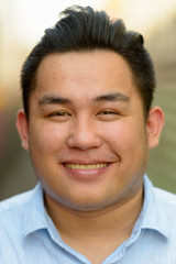 Obraz premium Face of happy overweight Asian tourist man smiling at railway train station