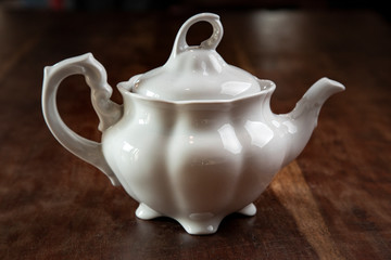 Teiera in porcellana bianca  , isolata su un tavolo dentro a una casa 