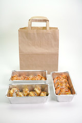 Japanese sushi rolls in foil containers on an isolated white background.
