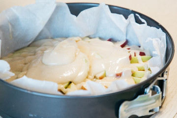 A woman preparing food in a bowl on a cutting board with a cake