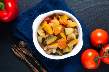 Food concept Homemade French organic Ratatouille in white bake ceramic bowl on blask slate stone board © TYSB