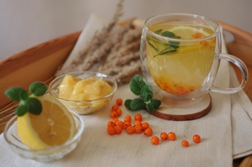 Hot healthy drink with buckthorn tea with lemon and honey on rustic background