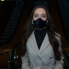 Woman with medical face mask near the escalator in underground. Woman wearing a protective mask against coronavirus. Facial hygienic mask for safety outdoor.